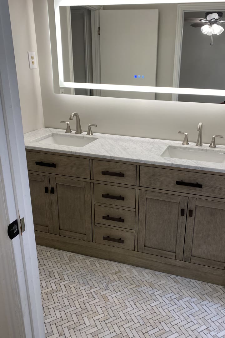 Double vanity with a lighted mirror and herringbone tile in the Caito home